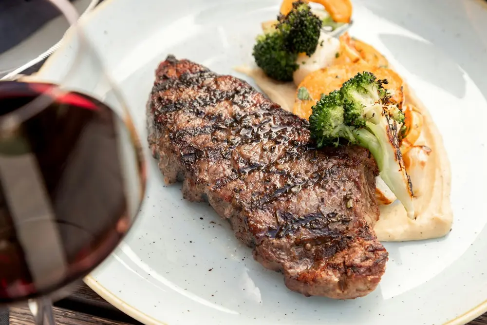 Pièce de bœuf, légumes et verre de vin rouge